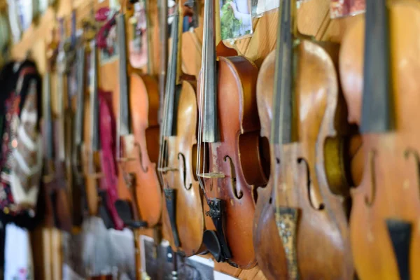 Багато антикварних скрипок висять на стіні. Крупним планом — стокове фото
