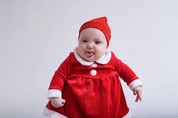 Dziecko w kostiumie Mikołaja pokazuje język. Białe tło. — Zdjęcie stockowe