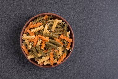 Fusilli pastası gri arka planda kasede. Çiğ İtalyan makarnası. Üst Manzara. Uzayı kopyala Şablon. Model.