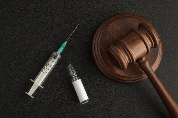 Syringe vial with an empty label and judges gavel or mallet law and. Laws and decisions against medicine.