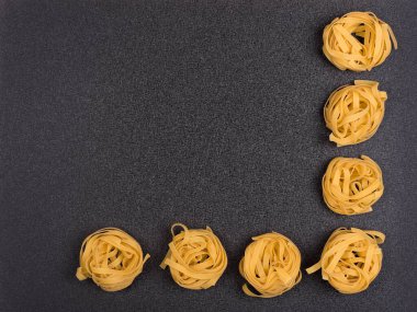 Gri arka planda spagetti yuvaları. Fettuccine veya Tagliatelle. Aşçı arkaplanı, kopyala.