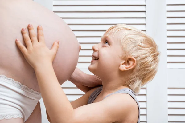 Roztomilý Blondýnka Chlapec Úsměvem Objímání Břicho Jeho Těhotné Matky — Stock fotografie
