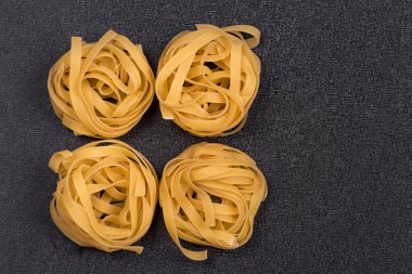 Gri arka planda Fettuccine veya Tagliatelle. Spagetti yuvaları. İtalyan mutfağı. Kuru pişmemiş makarna..