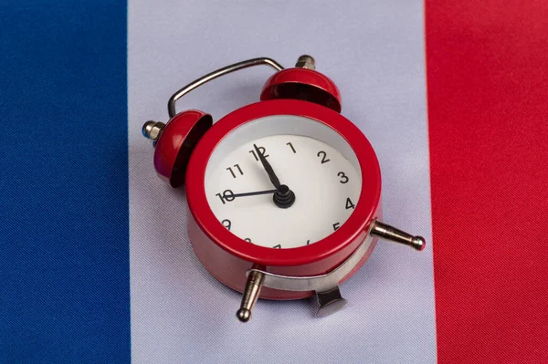 Flag of France and vintage alarm clock close up. Time to learn French.