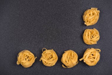 Gri arka planda spagetti yuvaları. Fettuccine veya Tagliatelle. Aşçı arkaplanı.