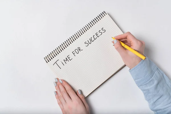 Female hands writes in notepad TIME FOR SUCCESS. White background