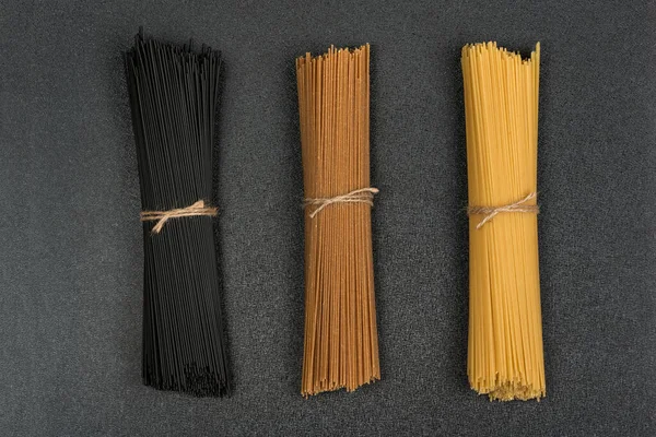 Svart Brun Och Gul Spaghetti Grå Bakgrund Italiensk Torkad Pasta — Stockfoto