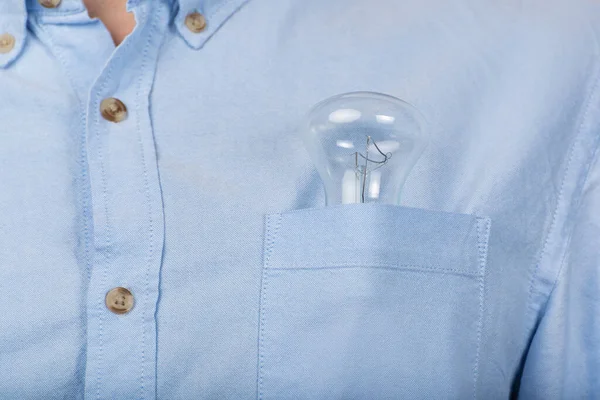 Incandescent lamp in the pocket of a man\'s shirt. Close-up.
