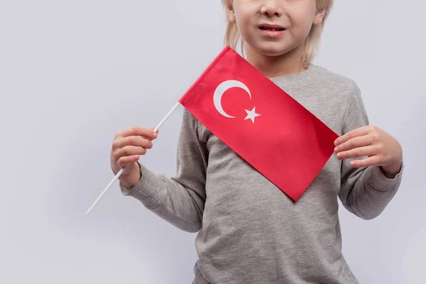 Child holds the flag of Turkey. Close up. Learning Turkish for children. Immigration to Turkey.