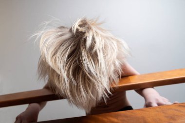 Sarı saçlı çocuk tırabzanın üzerine eğildi. Evde çocuğun güvenliği..