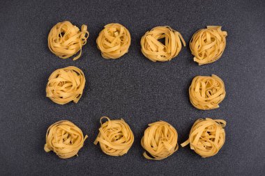 Gri arka planda Fettuccine veya Tagliatelle. Makarna arka planı. Spagetti yuvaları.