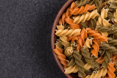 Fusilli pastası gri arka planda kasede. Çiğ İtalyan makarnası. Kapatın. Uzayı kopyala Model.