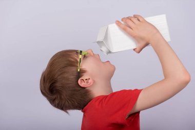 Beyaz arka planda süt ya da meyve suyu içen bir çocuk. Uzayı kopyala Şablon. Model.