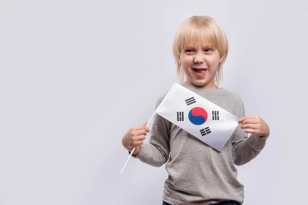 Jasnowłosy Chłopiec Przebiegłą Twarzą Trzymający Flagę Korei Południowej Białym Tle — Zdjęcie stockowe