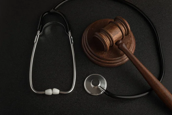 Gavel hammer of judge and stethoscop on black background. Law and medicine. Sentence on medical negligence