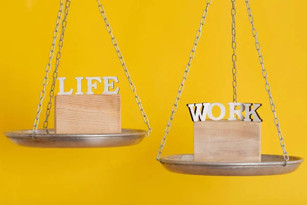 Work and life balance concept. Balance scales on yellow background close up.