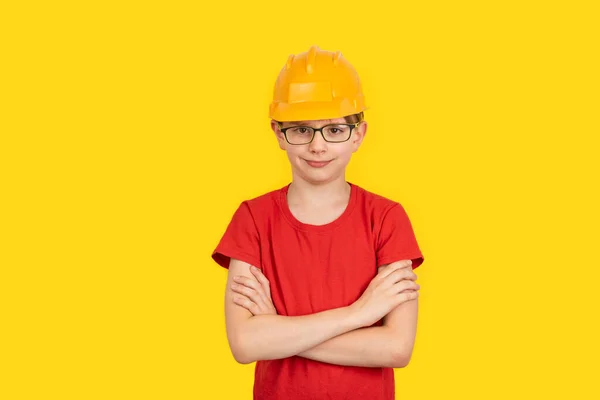 年轻男孩戴着黄色背景的保护橙色硬帽 建筑工人的职业 — 图库照片