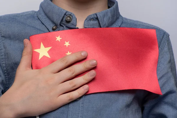 Child holds flag of China. Close up. Education in China. Study of Chinese language