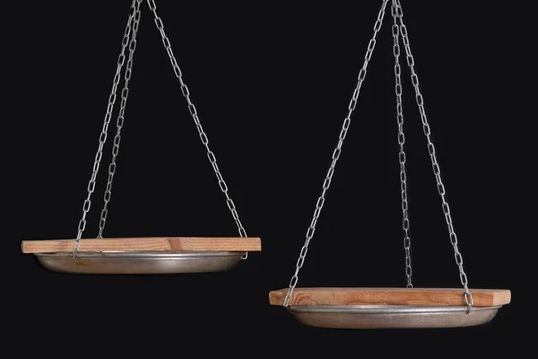 Balance scales and wooden coasters on black background close up. Copy space.