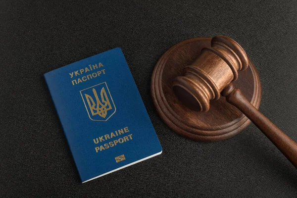 Judge gavel and passport of a citizen of Ukraine. Black background. Obtain citizenship