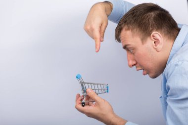 Market arabasını tutan ve parmaklarıyla ona bakan adam. Yan görüş. Beyaz arkaplan