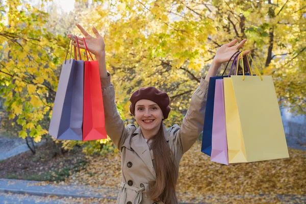 秋の公園の背景に買い物袋を持って幸せな若い女性 秋のセール — ストック写真