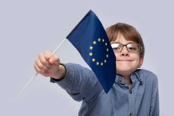 Boy in glasses holding flag of the European Union. Close up. Study in Europe.