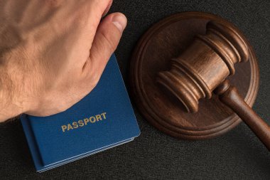 Erkek el, tahta tokmağın yanında pasaport tutuyor. Vatandaşlık al. Yasal göç