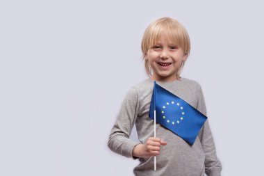 Beyaz arka planda elinde AB bayrağını tutan gülümseyen sarışın çocuk. Avrupa konsepti eğitimi.