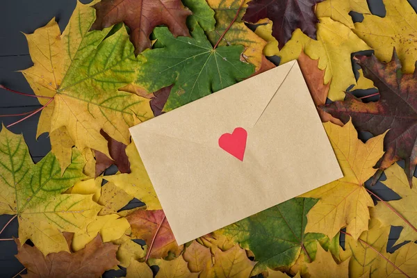 Letter on yellow fallen leaves. Envelope with heart