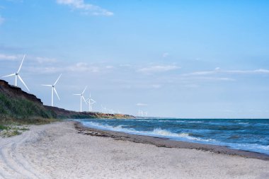 Deniz ve sahil arka planında rüzgar tekerlekleri. Rüzgar enerjisi. Alternatif enerji.