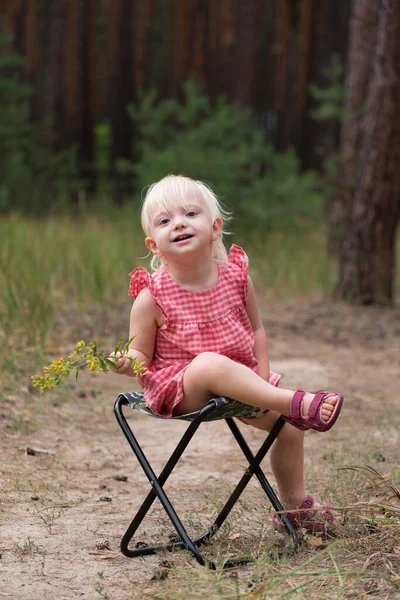 身穿太阳衣的小女孩在森林的背景下坐在椅子上 垂直框架 — 图库照片