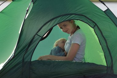 Annem bebeğini kamp çadırında emziriyor. Çocuklarla kamp yapmak..