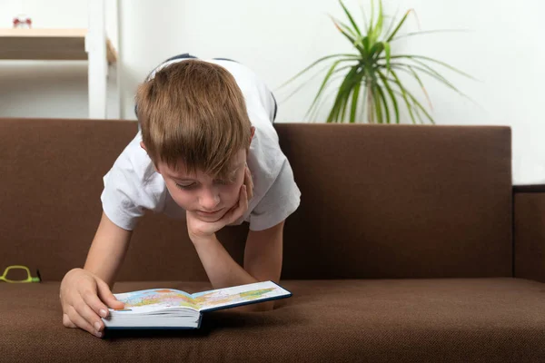 Kind Liegt Auf Der Couch Und Betrachtet Buch Hausaufgabenbetreuung — Stockfoto