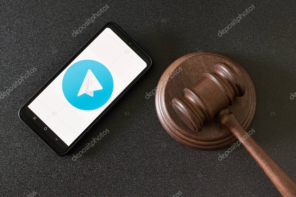 KHARKOV, UKRAINE - JUNE 25, 2020: Telegram app on smart phone screen and mallet of the judge. Telegram web-client.