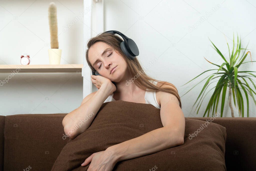 Beautiful young woman in headphones listen to relaxing music with closed eyes.