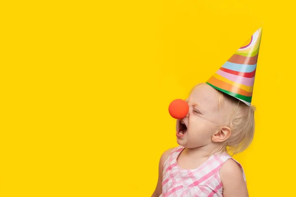 Unglückliches Kleines Mädchen Mit Festlichem Hut Und Clownsnase Auf Gelbem — Stockfoto