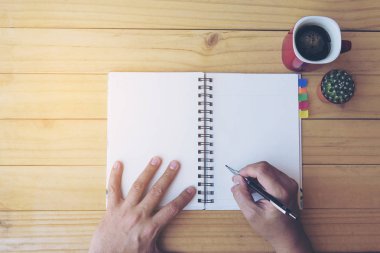 Ahşap masa kahve fincanı ve küçük kaktüs pot ile Not kitap yazma adamın üstten görünüm