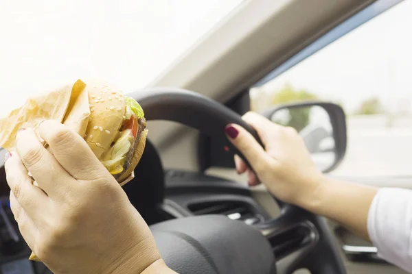 Žena Volantem Auta Jíst Hamburger — Stock fotografie