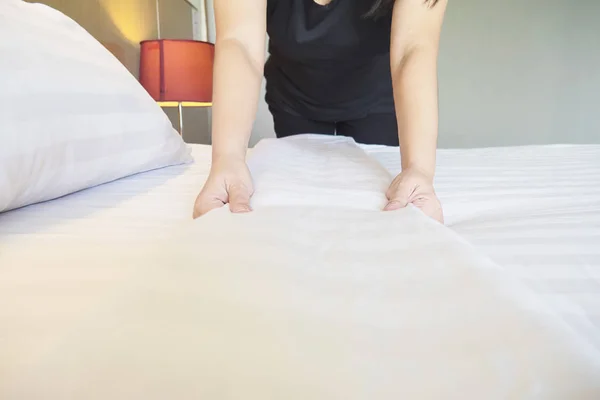 Lady hands set up white bed sheet in hotel room