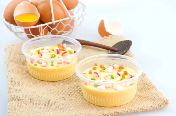 Thai steamed egg with fresh beaten egg in a basket and spoon decoration on sack background