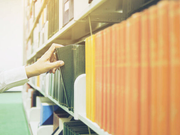 Man is selecting the book from bookshelf in a library