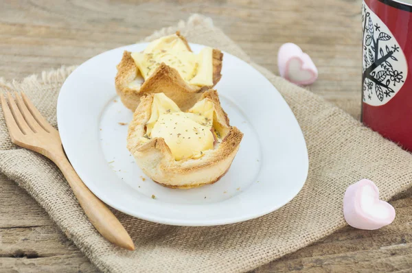Egg cheese bread toast on white dish with wooden fork and red coffee mug and heart marshmallow background