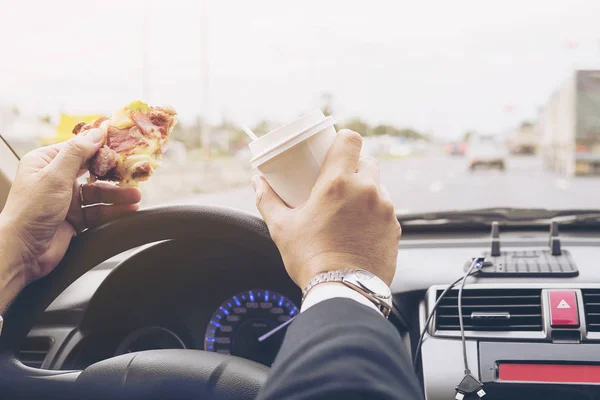 Man eating pizza and coffee while driving car dangerously