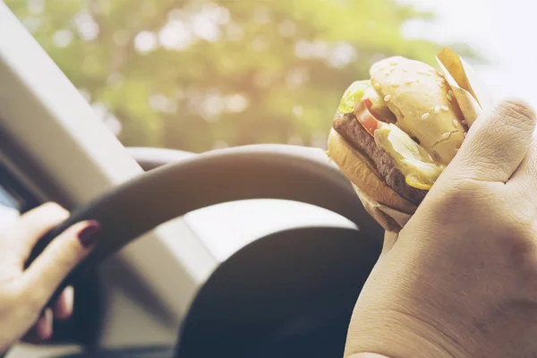 Žena Volantem Auta Jíst Hamburger — Stock fotografie