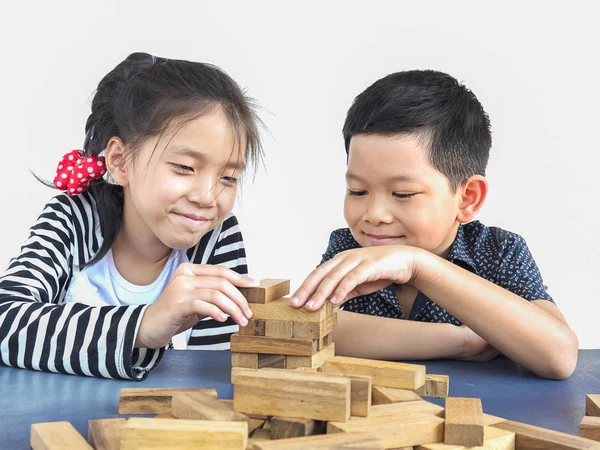 Children are playing jenga, a wood blocks tower game for practicing their physical and mental skill