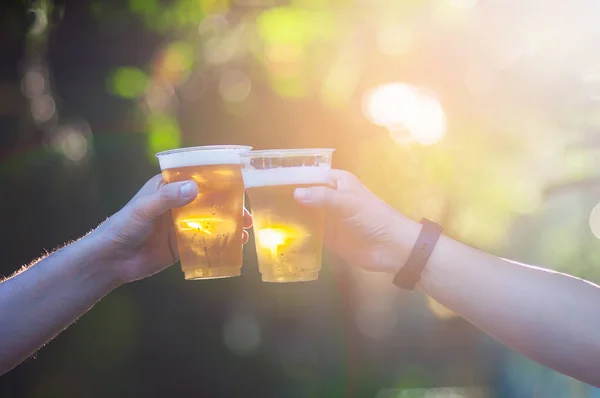 Celebration beer cheers concept - close up hands holding up glasses of beer of people group in outdoor party during their victory competition or successful task meeting