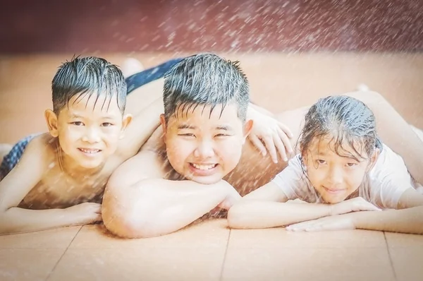 暑い季節の間に噴霧水で子供たちが喜んで遊んでいます — ストック写真