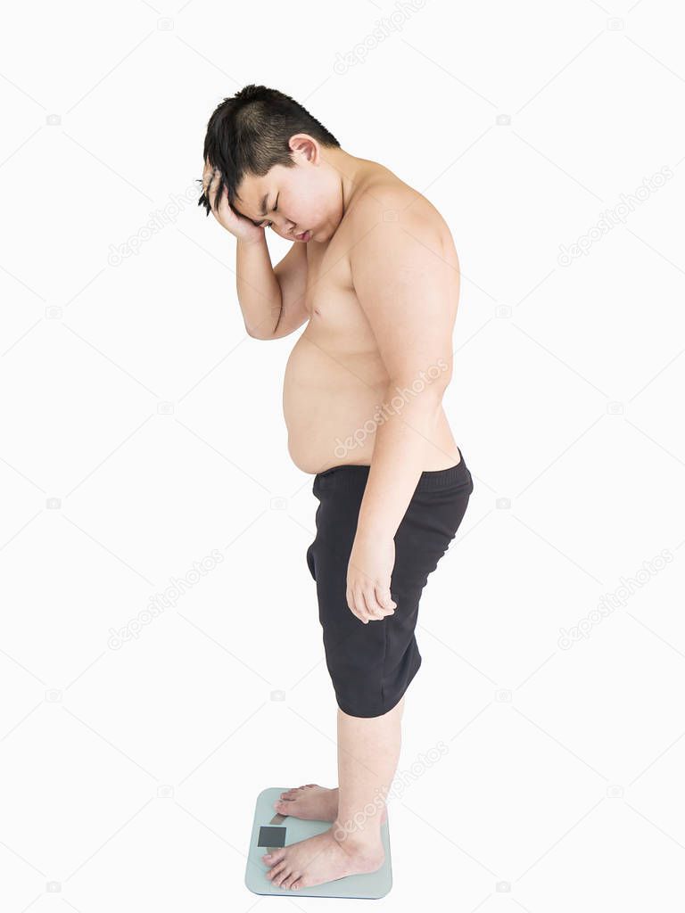 Fat asian boy disappointing with fatness while standing on weighing machine