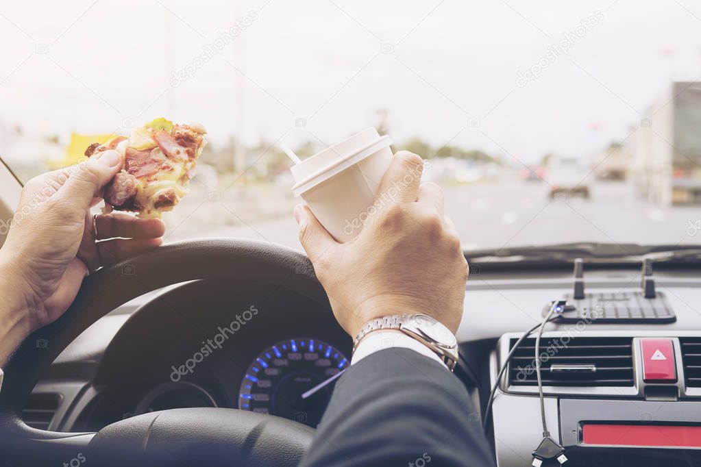 Man eating pizza and coffee while driving car dangerously